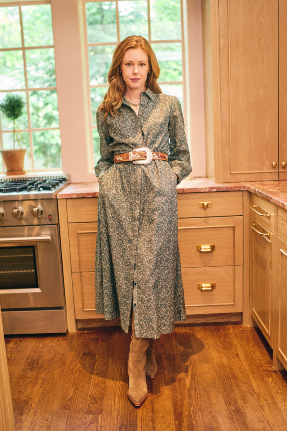 Woman standing in a kitchen wearing a long patterned dress.