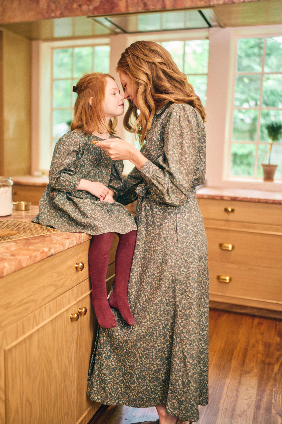 Woman and child in matching floral dresses in a kitchen