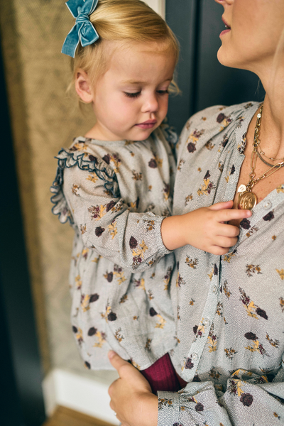 Woman holding a young child wearing a floral dress with a blurred background