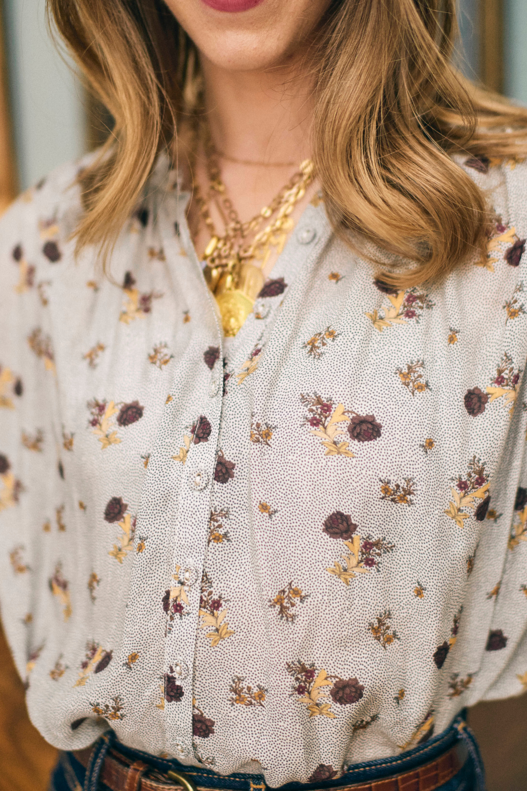 Close-up of a person wearing a floral blouse with a blurred background