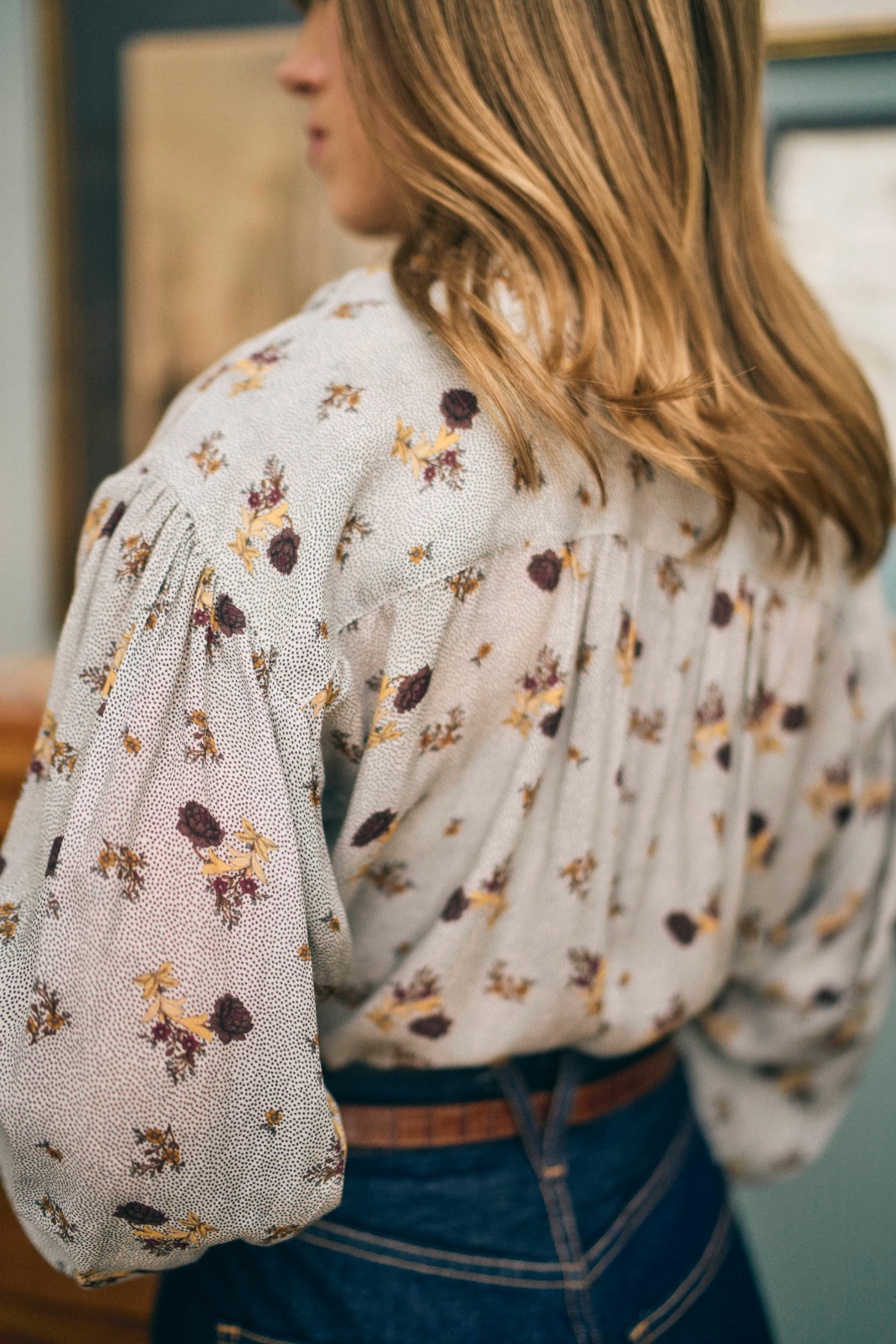 Person wearing a floral blouse with puffed sleeves indoors.