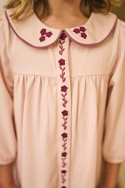 Pink dress with embroidered floral details on a blurred background