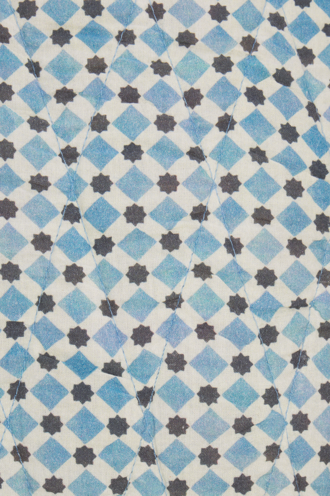 Patterned fabric with blue and black diamond shapes on a white background