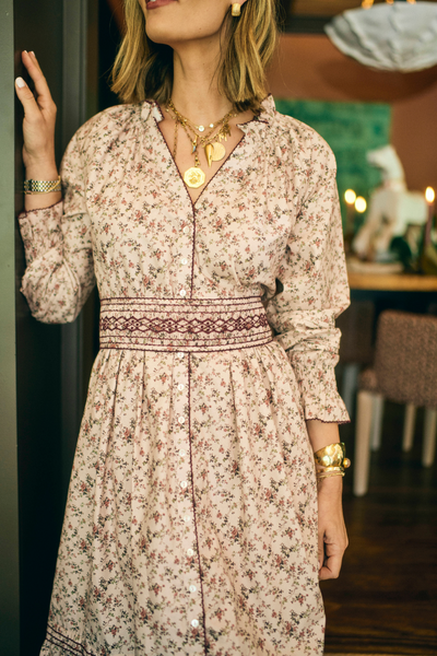 Woman wearing a floral dress with jewelry in an indoor setting