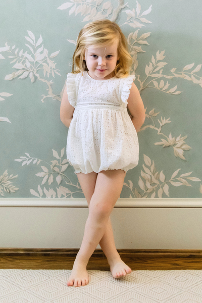 Image of little girl in a white eyelet playsuit