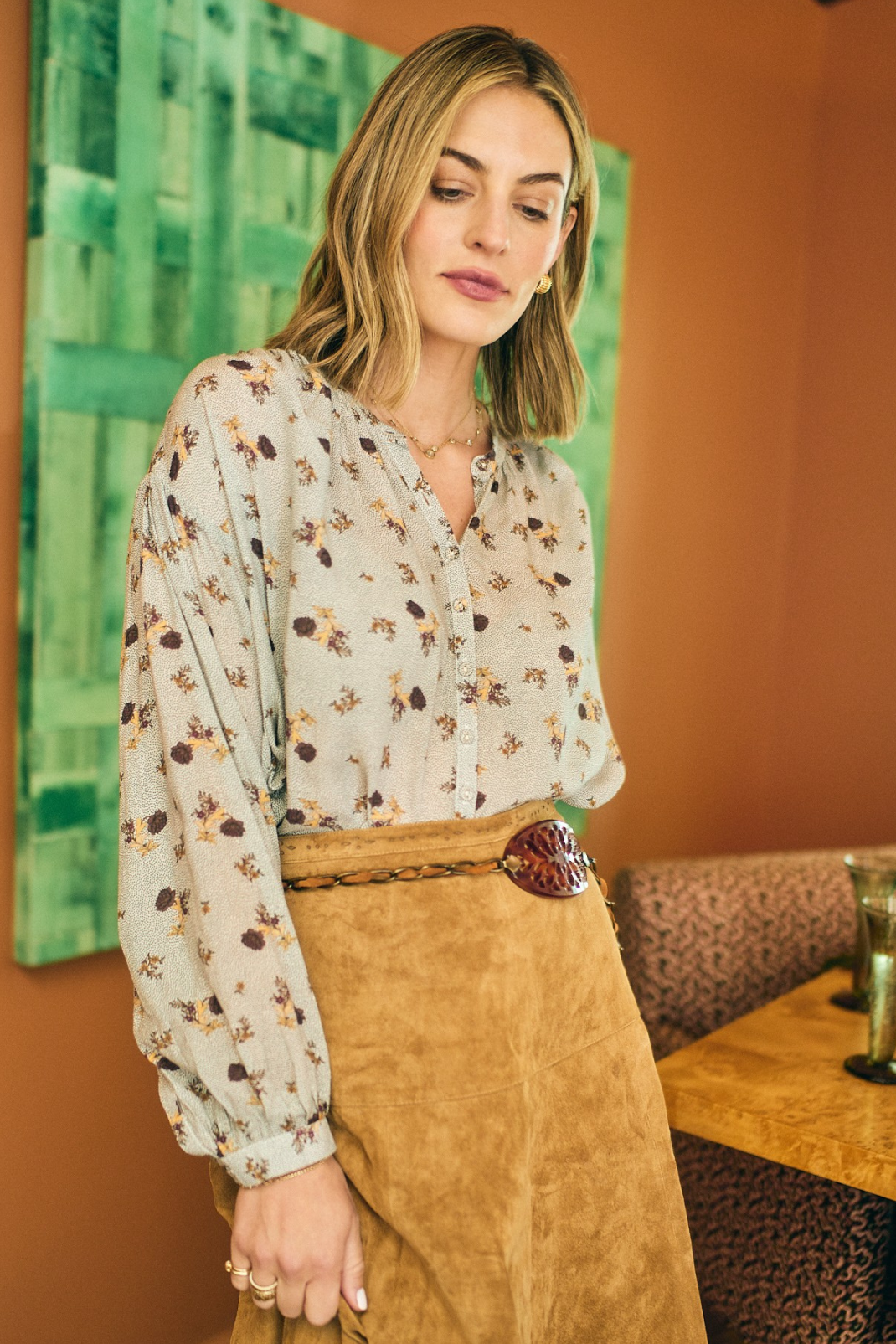 Woman wearing a floral blouse and brown skirt in an indoor setting