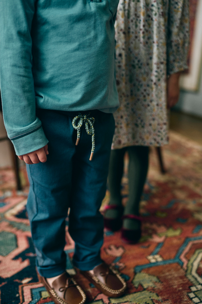 Close up photograph of a boy wearing a blue top and navy pants