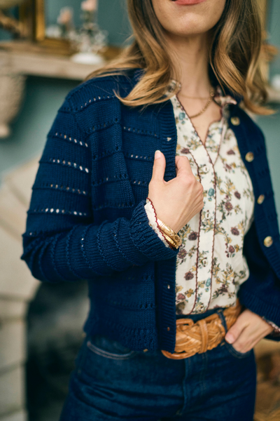 Woman wearing a navy blue cardigan over a floral blouse with a blurred background
