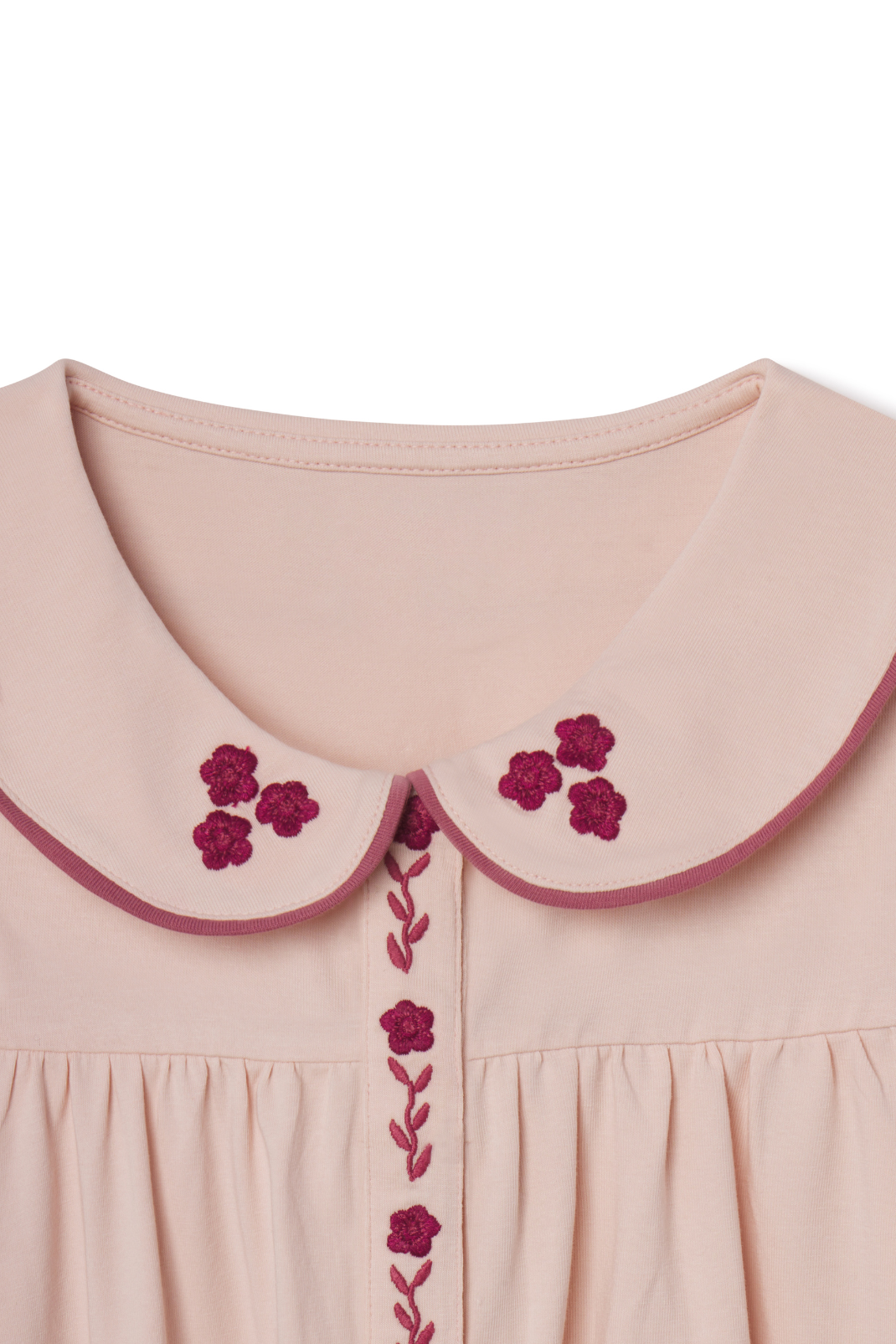 Close-up of a pink dress with floral embroidery on a white background