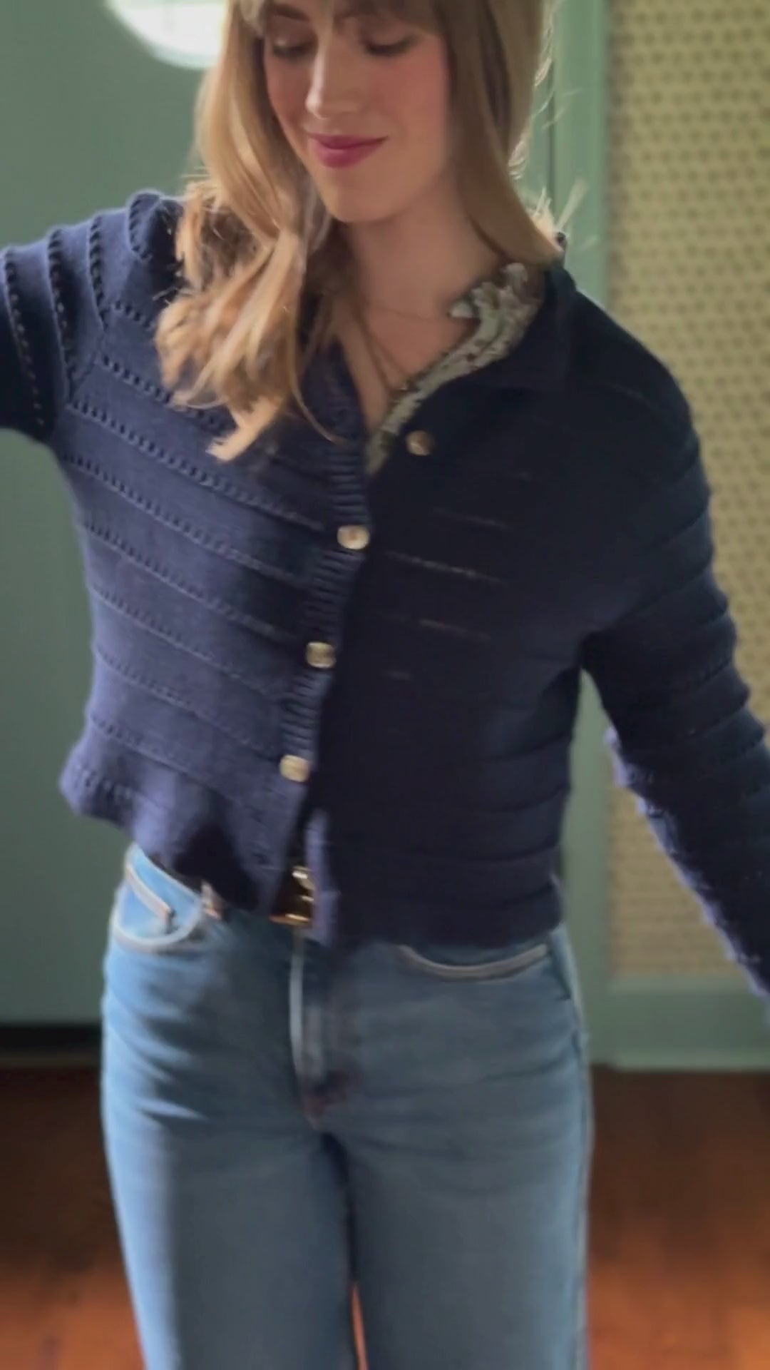 Video of a woman wearing a deep blue open knit cardigan