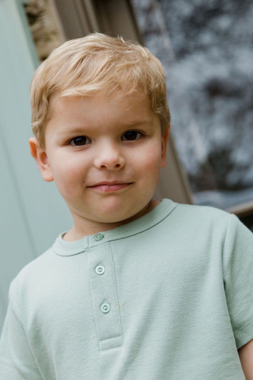 Close up lifestyle shot of a little boy wearing the Will Top in aloe