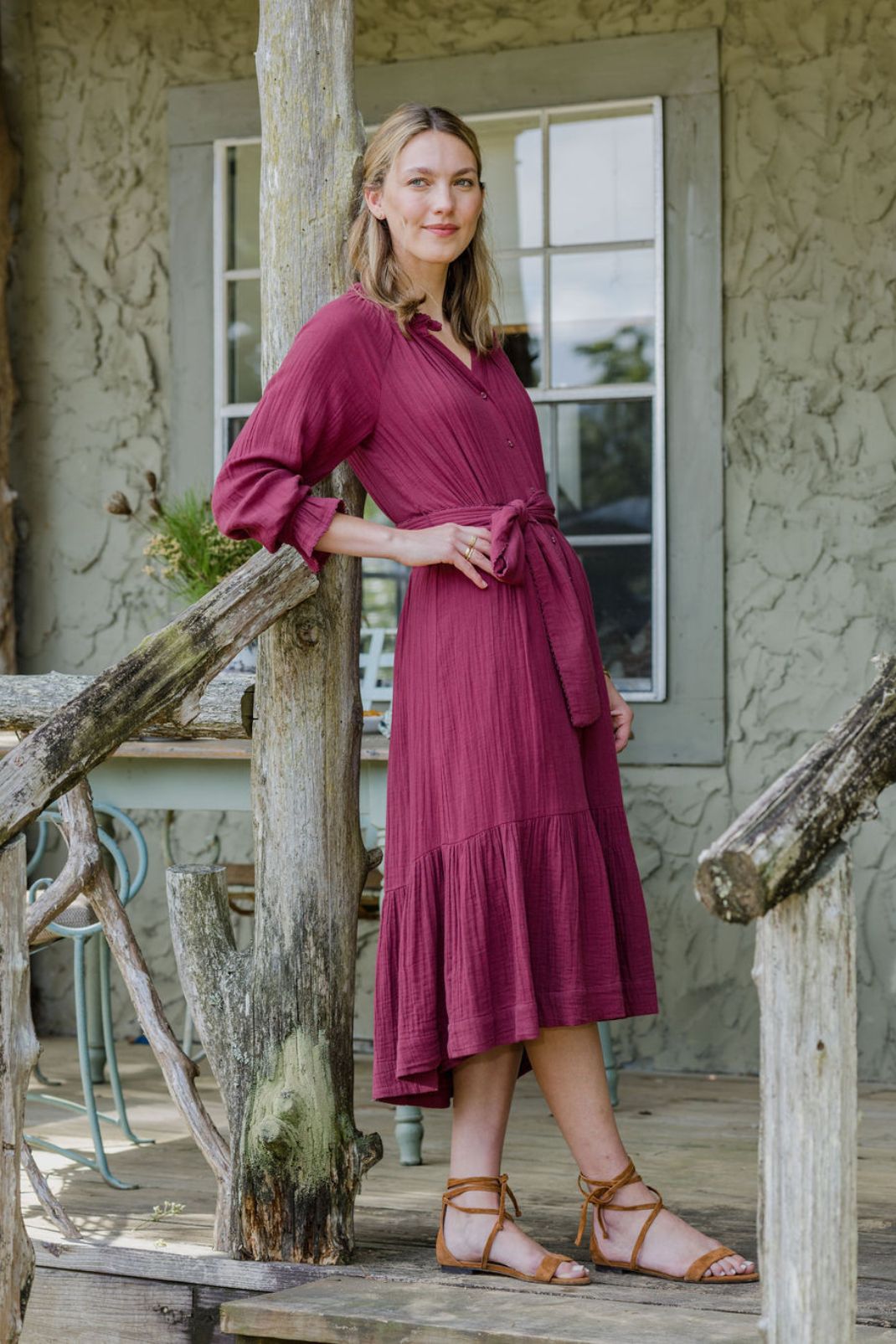 Lifestyle shot of woman standing outside wearing the Vivianne Dress in Cranberry