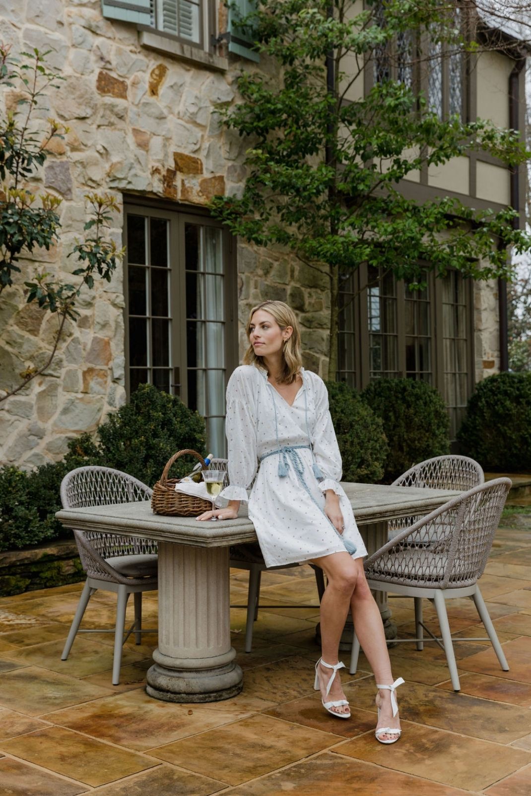 Lifestyle image of a woman sitting outside on a table wearing the Isla Dress