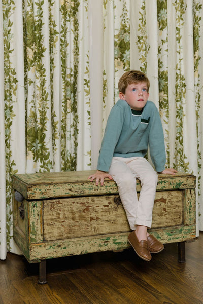 Lifestyle image of a boy sitting inside wearing the Stratton Sweater and Benjie Pants