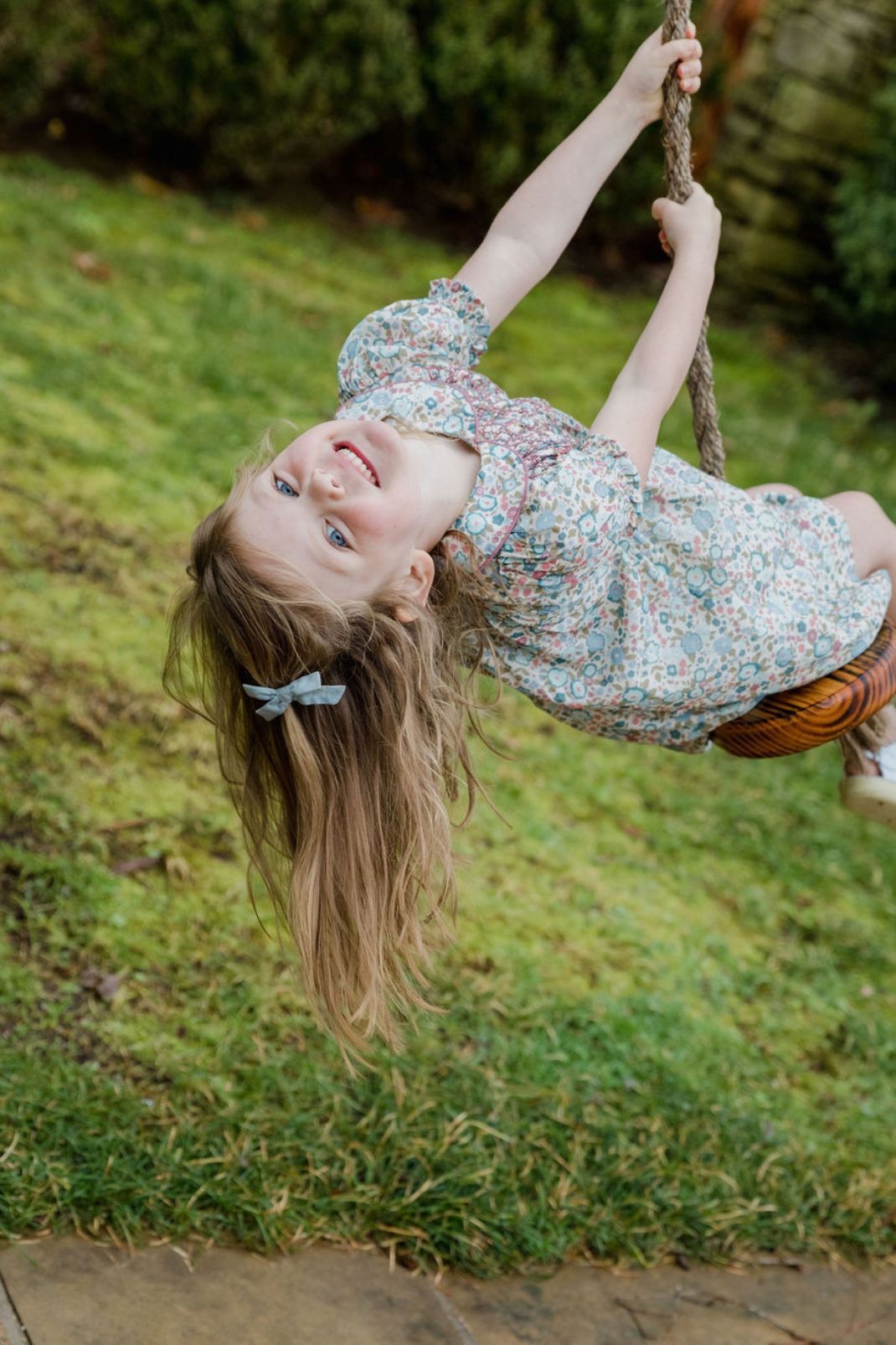 Little girl swinging outside wearing the Emmy Dress in floral breeze