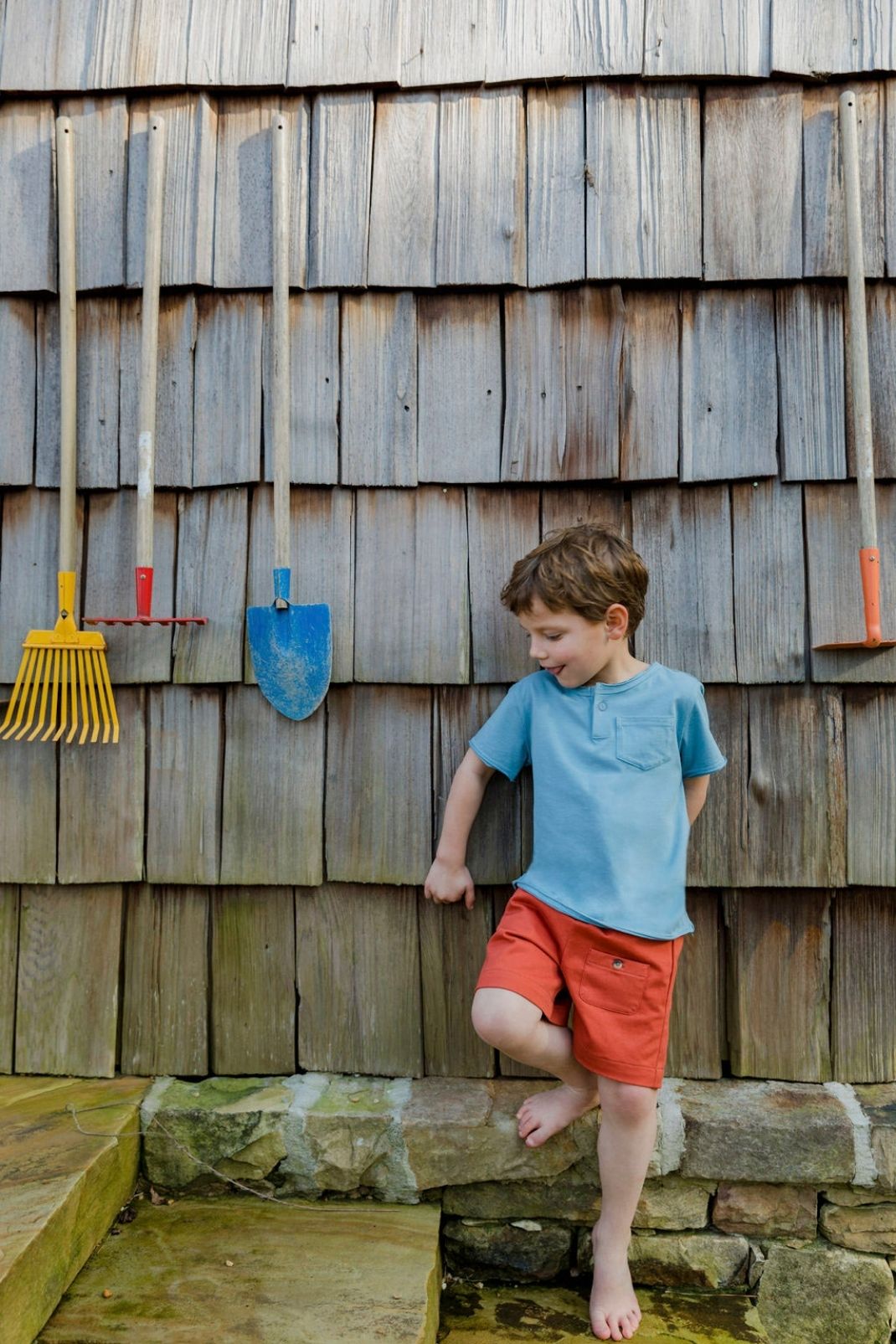 Little boy walking up steps outside wearing the Charlie Tee in sleepy blue and Graham Shorts in brushed pepper